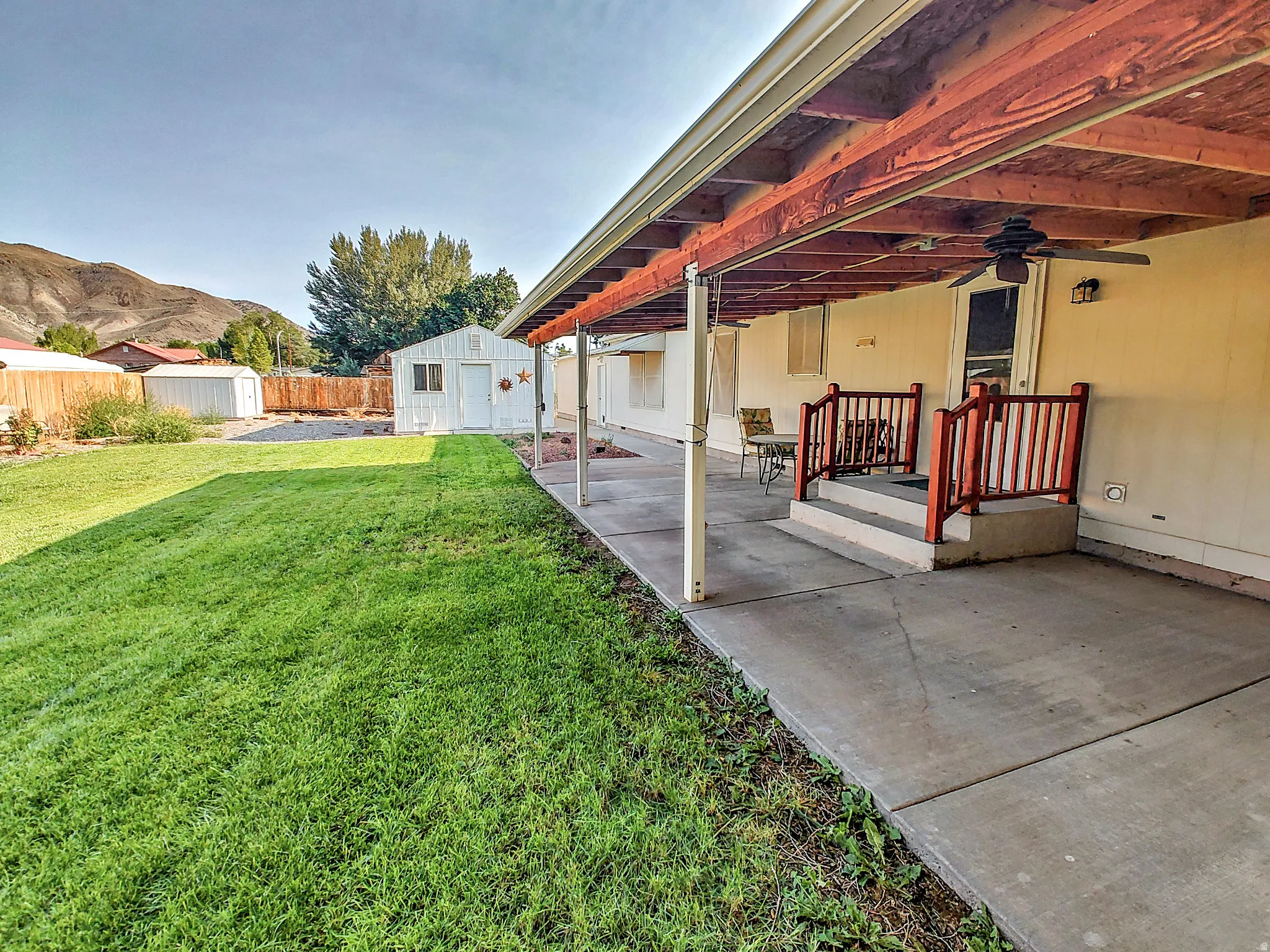 Expansive concrete patio with a covered section, featuring a ceiling fan and integrated lighting