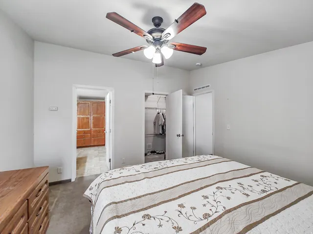 Spacious bedroom featuring wood-finish flooring, ceiling fan with integrated lighting, and generous closet storage