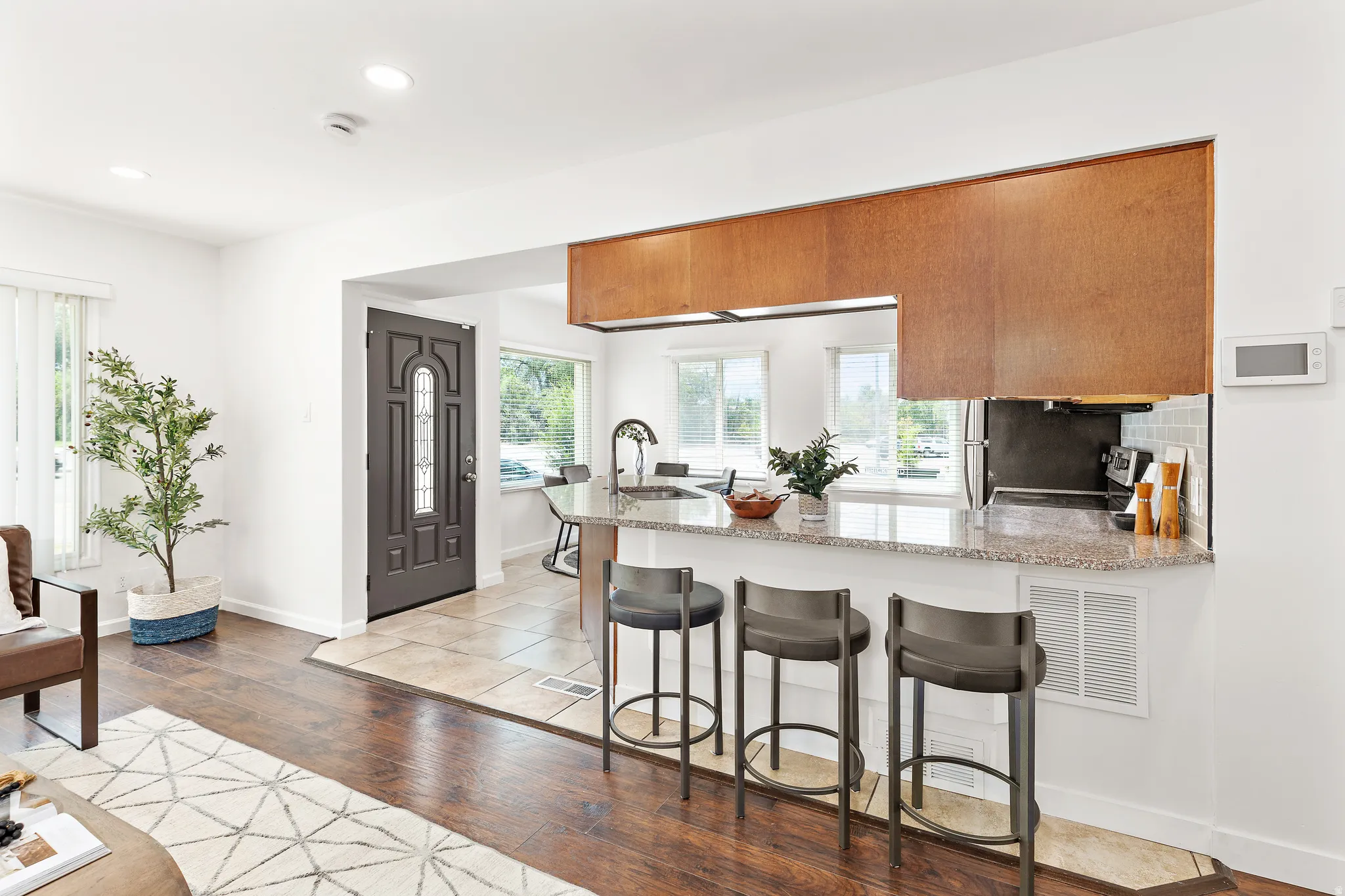 Kitchen pass-through with a stone-finish countertop and breakfast bar seating for three
