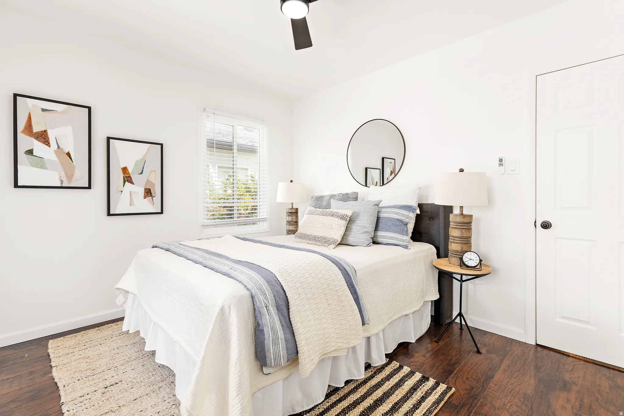 White paneled interior door, wood-finish flooring, and a ceiling fan with integrated lighting