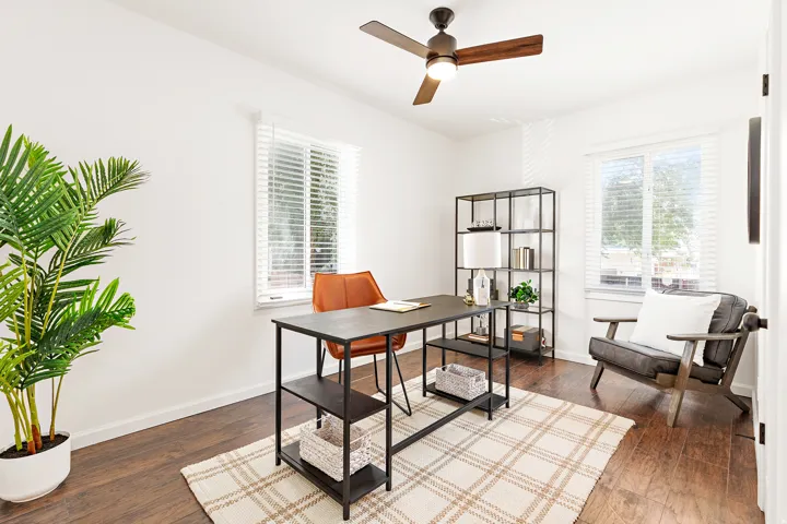 Bright room featuring dark wood-finish flooring, white walls, and two windows with white blinds