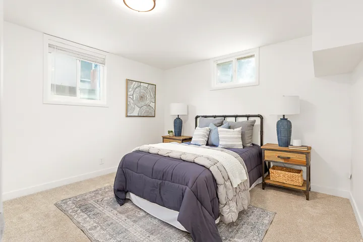 Carpeted room featuring white walls and two windows with blinds