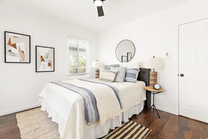White paneled interior door, wood-finish flooring, and a ceiling fan with integrated lighting