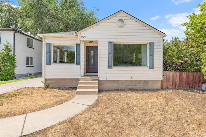 Exterior featuring white horizontal siding, a gabled roofline, and blue decorative window shutters