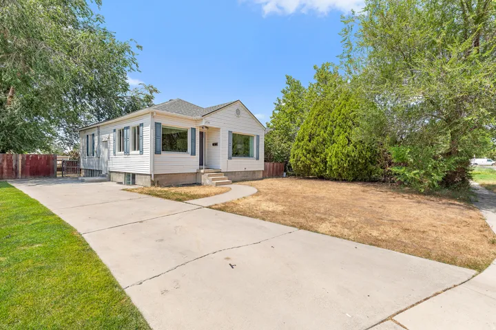 White siding exterior with blue window shutters, concrete driveway, and a curved front walkway