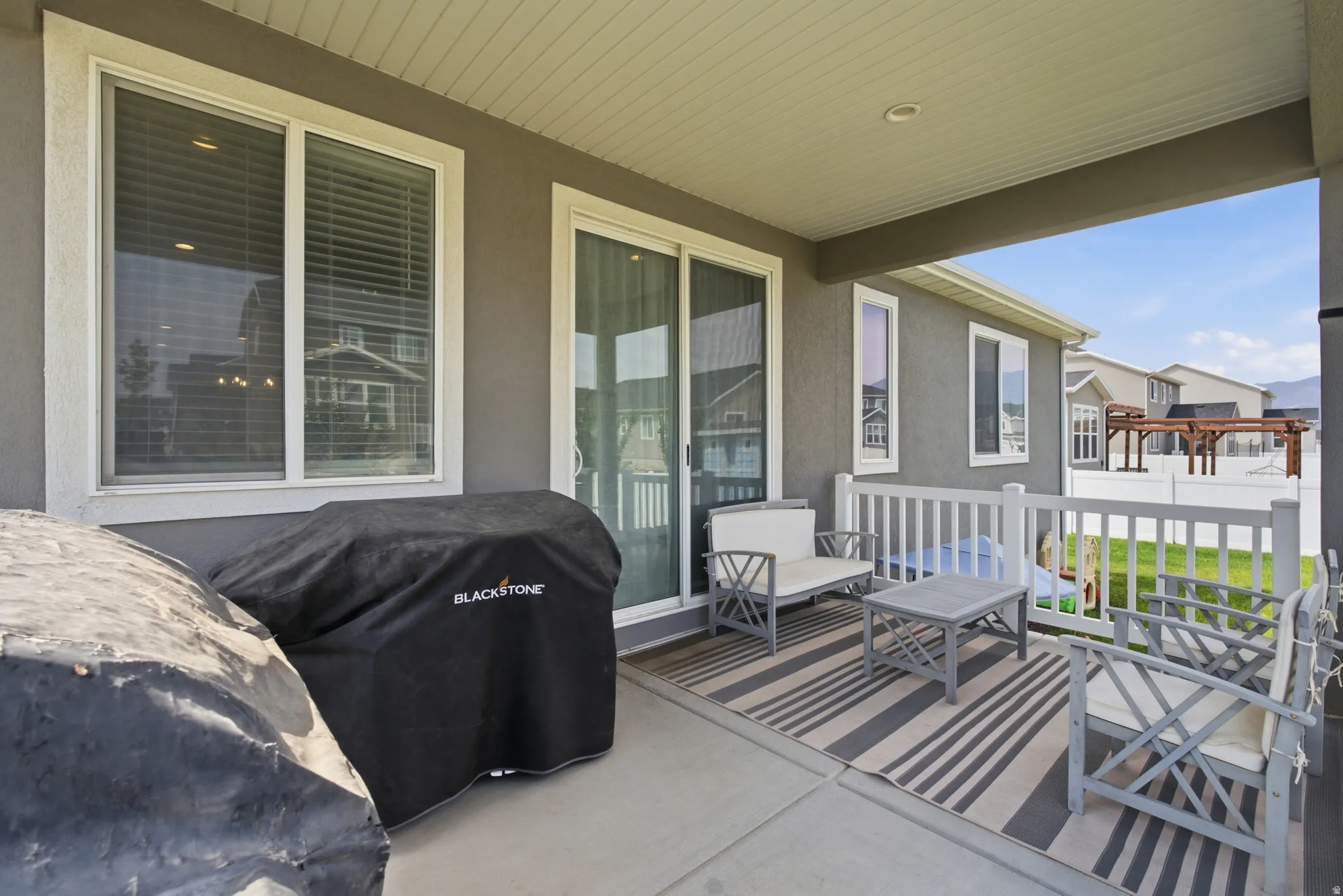 Covered patio with concrete flooring, white railing, and sliding glass door access