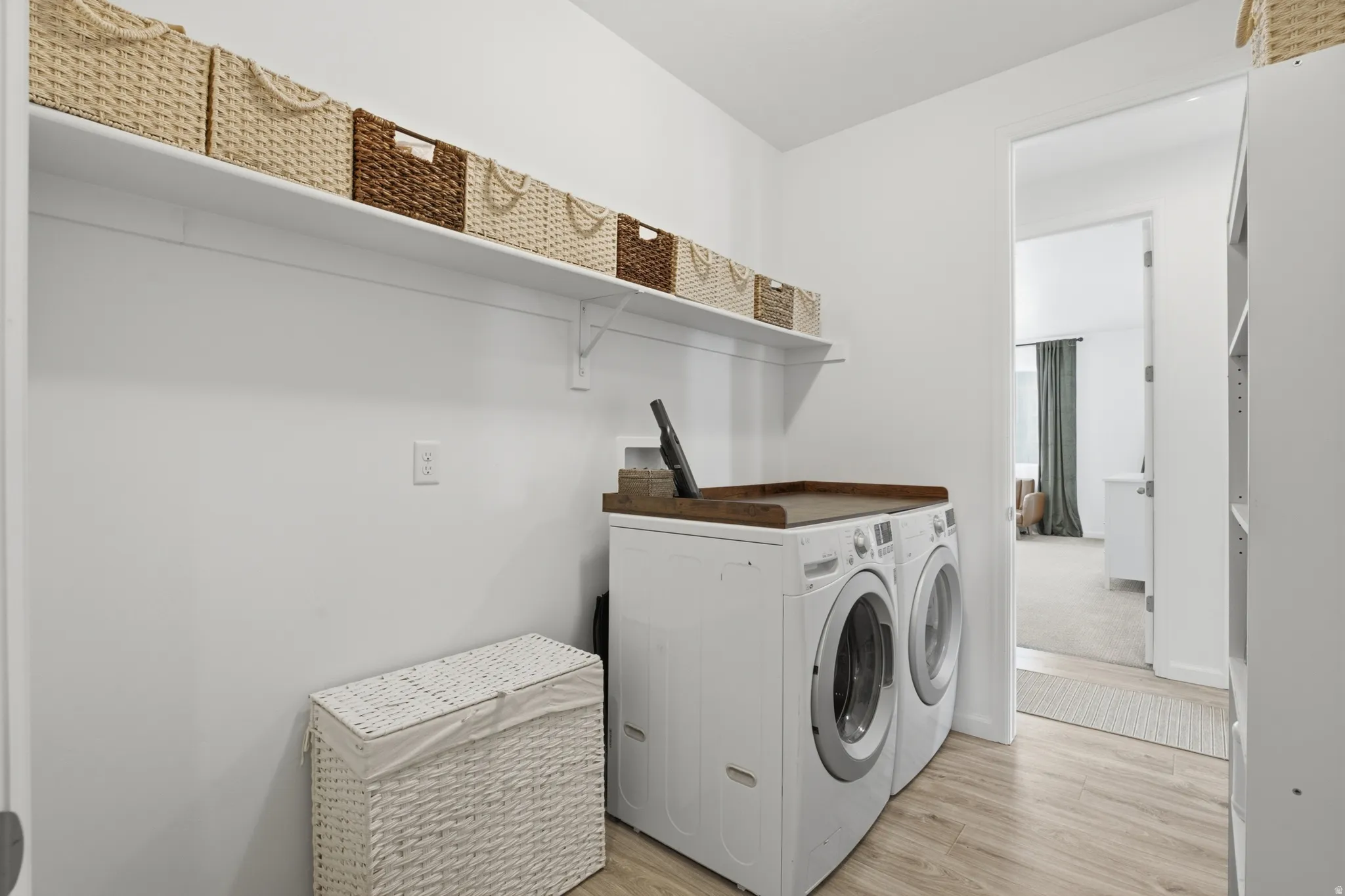 Wood-finish flooring with a white washer and dryer set, featuring a wood-tone countertop