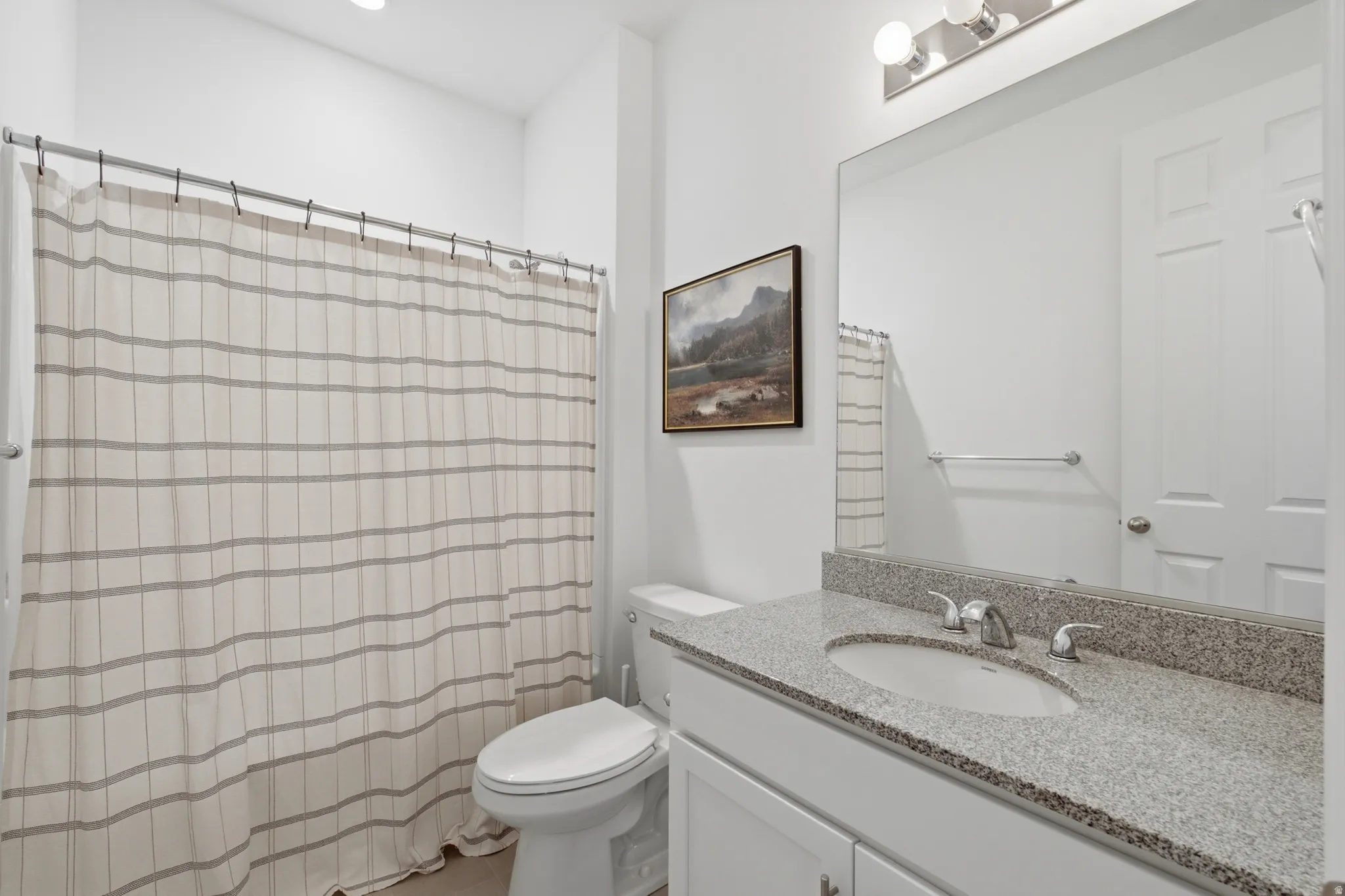 Bathroom featuring a single vanity with stone countertop, undermount sink, and polished chrome faucet
