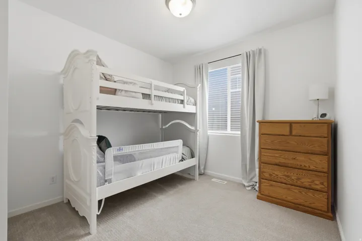 Light-colored wall-to-wall carpeting with white walls and a single window with blinds