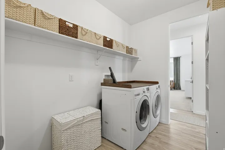 Wood-finish flooring with a white washer and dryer set, featuring a wood-tone countertop