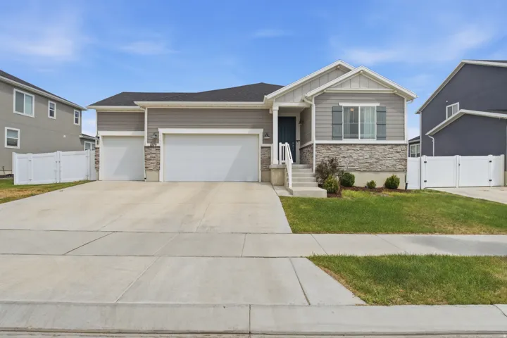 Front exterior featuring a multi-tone siding and stone facade, two-car garage, covered porch entrance, and a well-maintained lawn
