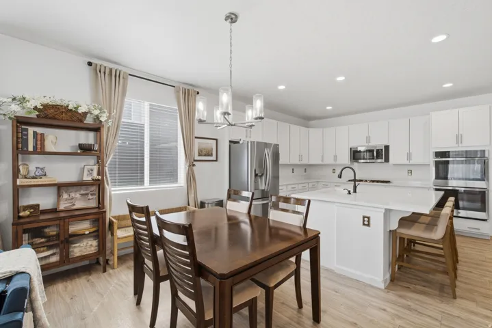 Kitchen featuring white cabinetry, stainless steel appliances, a center island with seating, and light wood-finish flooring