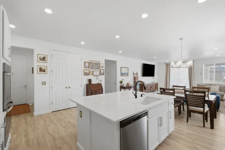 Open-concept kitchen with a central island, recessed lighting, wood-finish flooring, and white cabinetry
