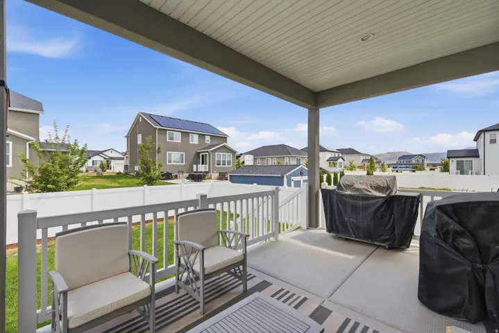 Covered patio with concrete flooring, white railing, and a fenced backyard