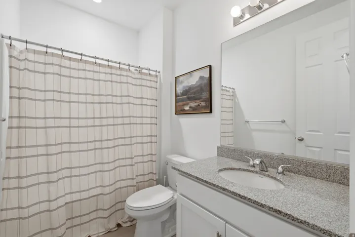 Bathroom featuring a single vanity with stone countertop, undermount sink, and polished chrome faucet
