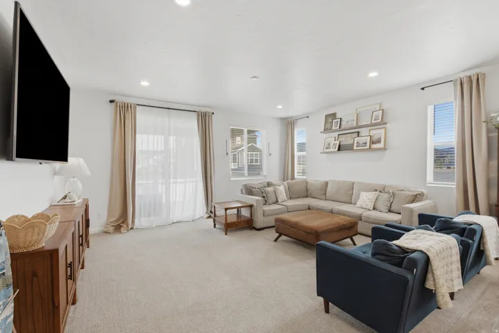 Recessed lighting, light-toned carpeting, multiple windows, and a wall-mounted display