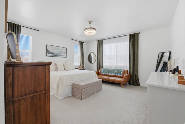 Carpeted flooring, white walls, multiple windows with blinds, and a built-in ceiling light fixture