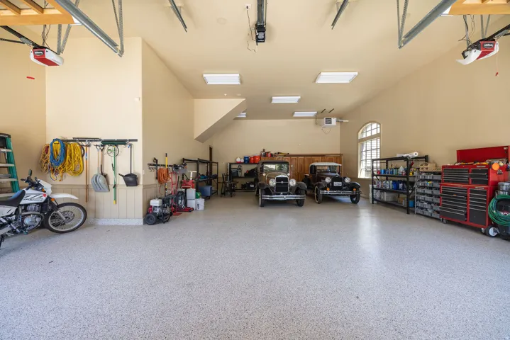 Spacious garage featuring a speckled epoxy flooring, vaulted ceilings, and dual automatic garage door openers