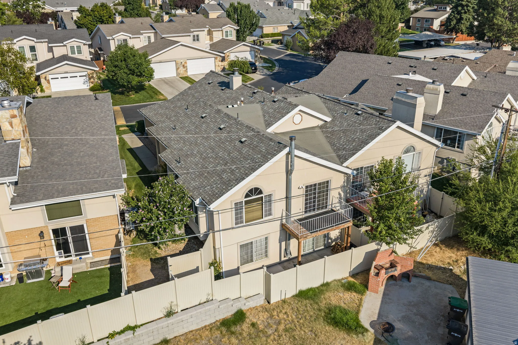 Pitched shingle roof, arched transom window, upper-level balcony, and a fenced perimeter