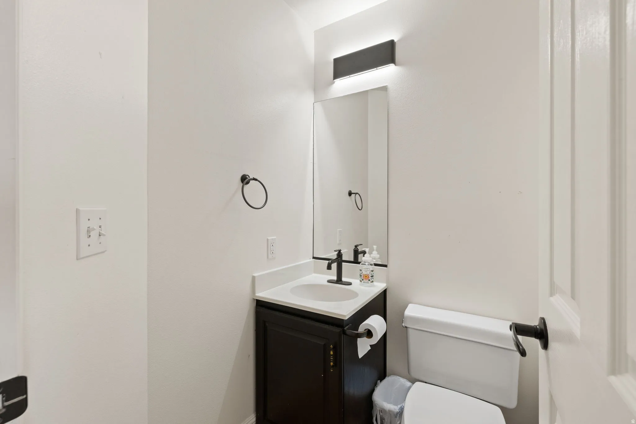 Powder room with a dark wood-finish vanity, white countertop, and integrated sink