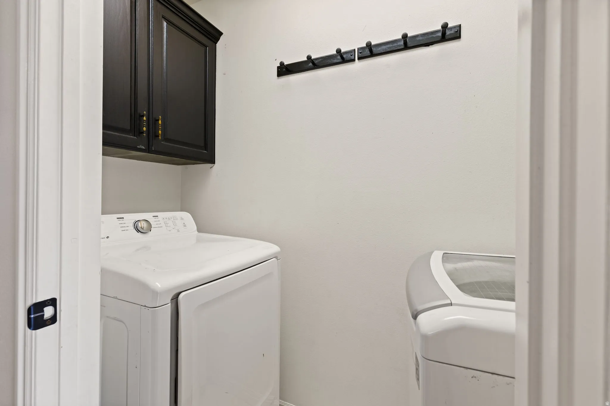 Built-in upper cabinetry with dark finish, wall-mounted coat hooks, and durable flooring