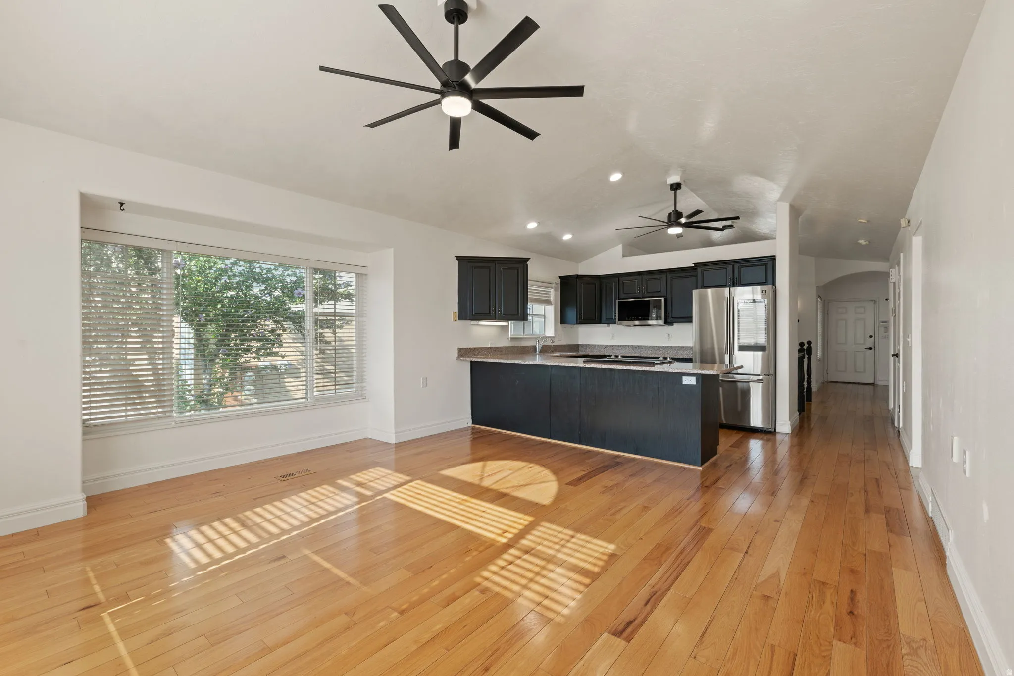 Hardwood flooring throughout, featuring a kitchen with dark cabinetry, stainless steel appliances, and an integrated kitchen island