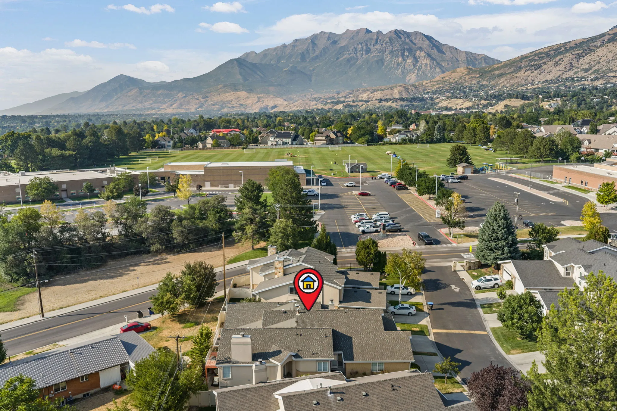 Mountain backdrop, green spaces, paved parking areas, surrounding residential architecture, and roads