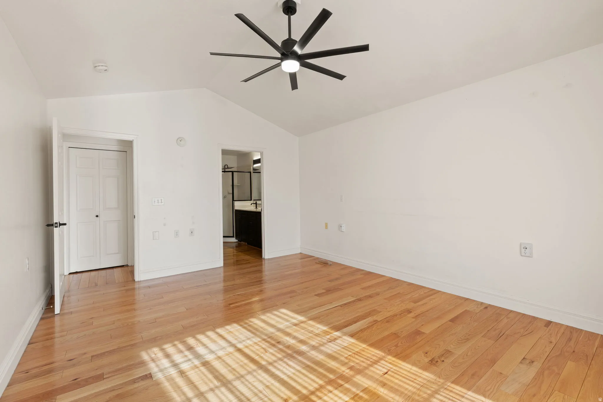 Hardwood flooring, vaulted ceiling, contemporary ceiling fan, white paneled doors, and access to a full bathroom
