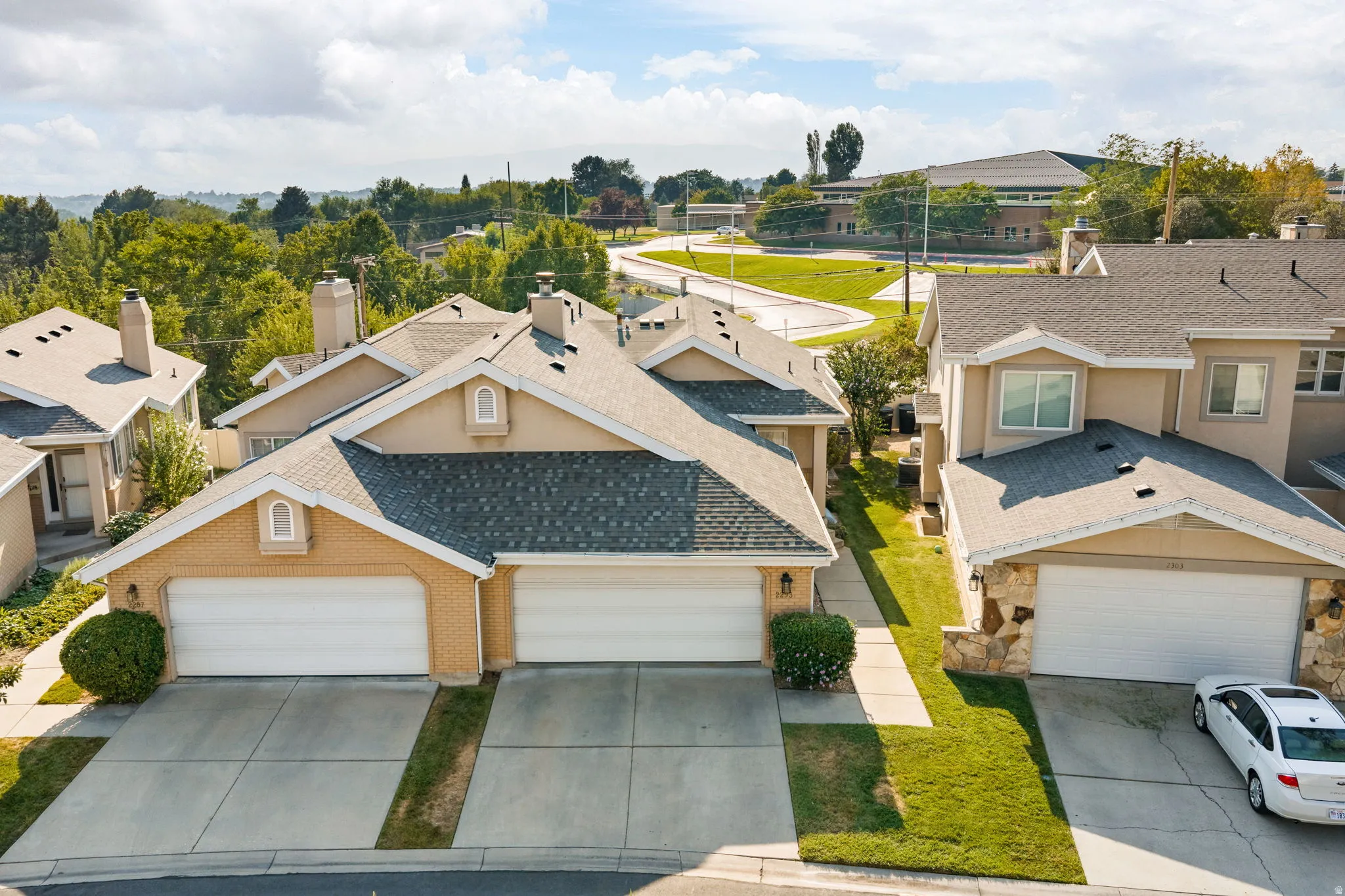 Stucco exterior with brick accents, attached two-car garage, concrete driveway, and pitched shingle roof