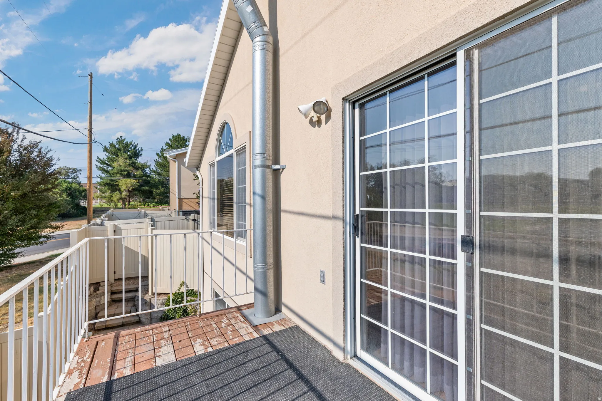 Balcony featuring painted metal railing, a sliding glass door with grid panes, and an arched window