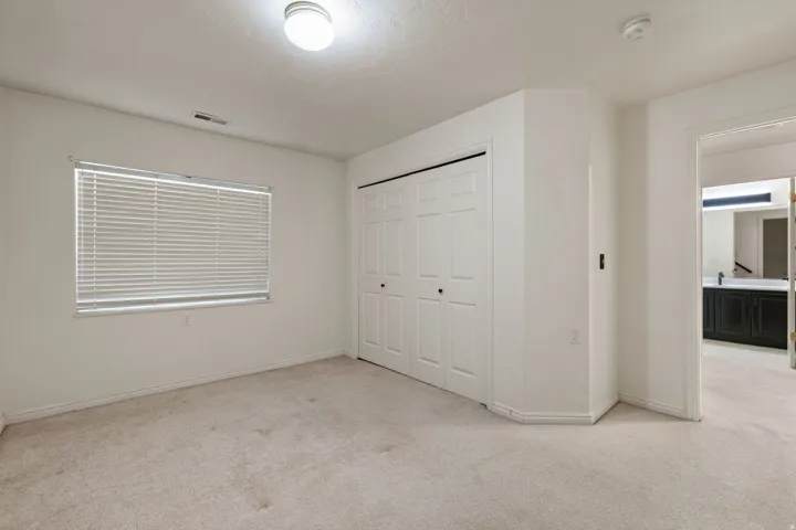 White walls, light-toned carpeting, window with blinds, bi-fold closet doors, and recessed ceiling lighting
