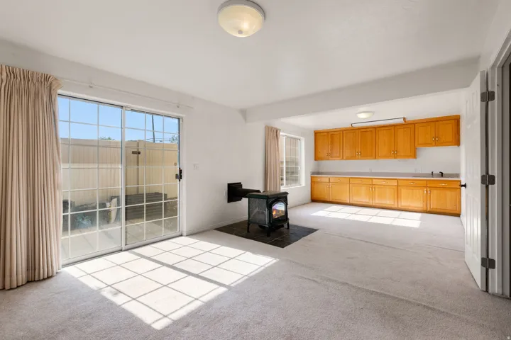 Built-in cabinetry with extensive counter space, sliding glass doors, carpet flooring, and a freestanding stove with a dark tile hearth