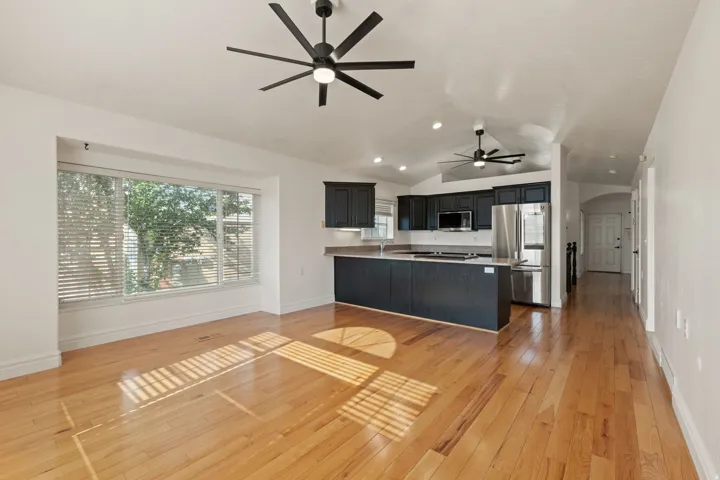 Hardwood flooring throughout, featuring a kitchen with dark cabinetry, stainless steel appliances, and an integrated kitchen island
