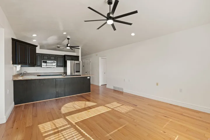 Open-concept living area featuring wood-finish flooring, vaulted ceilings, and recessed lighting