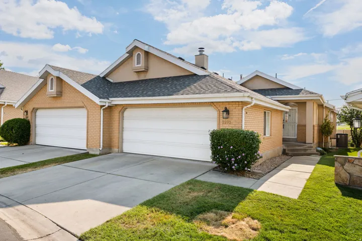 Brick facade with stucco accents, dual attached garages, concrete driveway, and mature landscaping