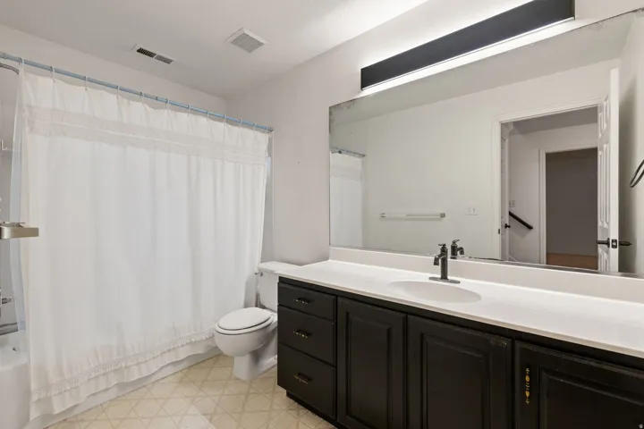 Bathroom featuring a single vanity with dark cabinetry, white countertop, and an integrated sink