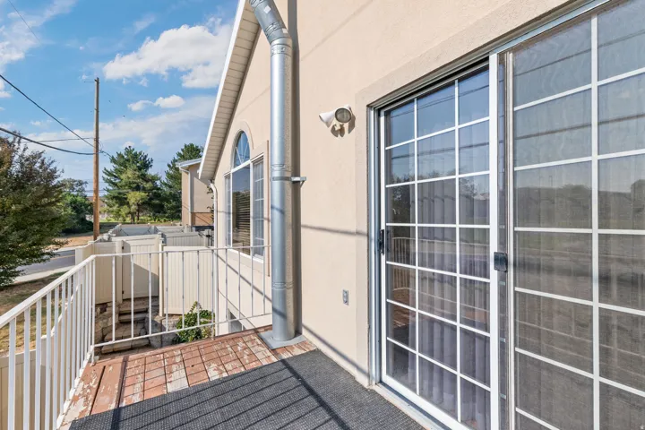 Balcony featuring painted metal railing, a sliding glass door with grid panes, and an arched window