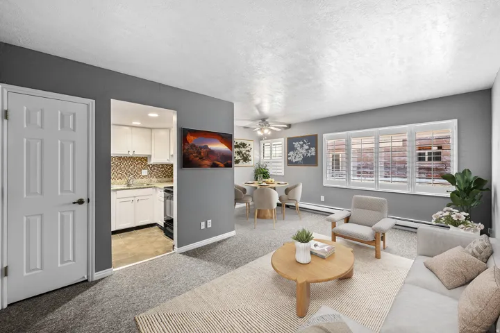 Open concept living area featuring a ceiling fan, carpet flooring, and large windows with plantation shutters