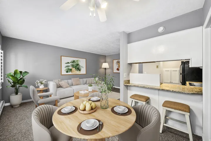 Dining area with wood-finish flooring, overhead ceiling fan, and direct access to a kitchen pass-through with a stone-finish countertop