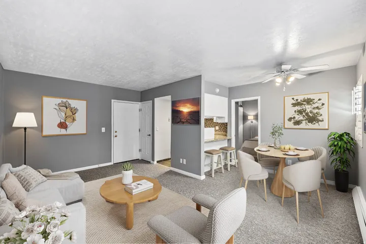 Living area featuring gray wall finishes, carpet flooring, a ceiling fan with light fixture, and an open breakfast bar with stone-finish countertop