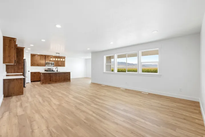 Open-concept living space featuring wood-finish flooring, recessed lighting, and a kitchen with wood cabinetry and an island