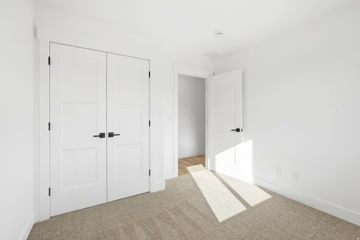 Neutral wall finishes, recessed lighting, and light-toned carpet flooring