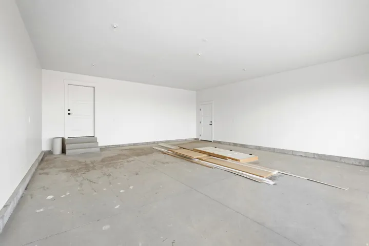 Concrete flooring with light-colored walls and a door with three horizontal panels