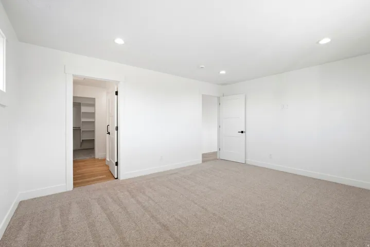Carpeted room with recessed lighting, an interior window, and a white paneled door with black hardware