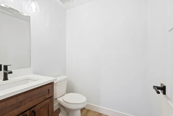 Wood-finish flooring with white trim, a dark wood-finish vanity with an integrated sink, and a black matte faucet