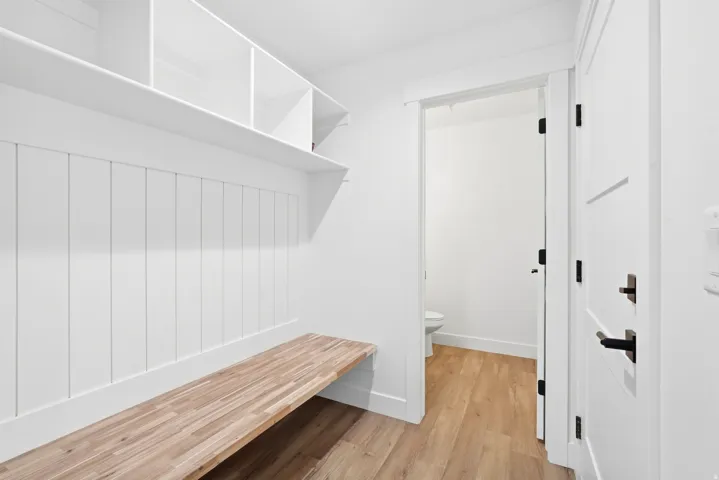 Built-in shelving and bench seating, wood-finish flooring, white paneling, and a modern interior door with dark hardware