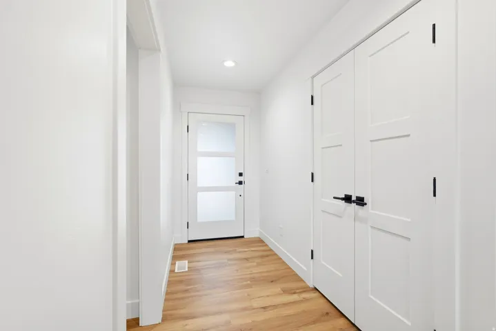 Entryway featuring wood-finish flooring, recessed lighting, a modern front door with frosted glass panels, and white paneled doors with matte black hardware