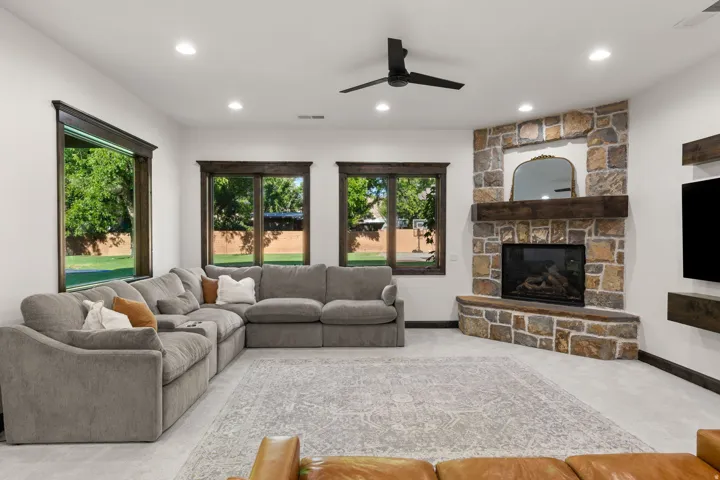 Spacious living area featuring a corner stone fireplace with a substantial wood mantel