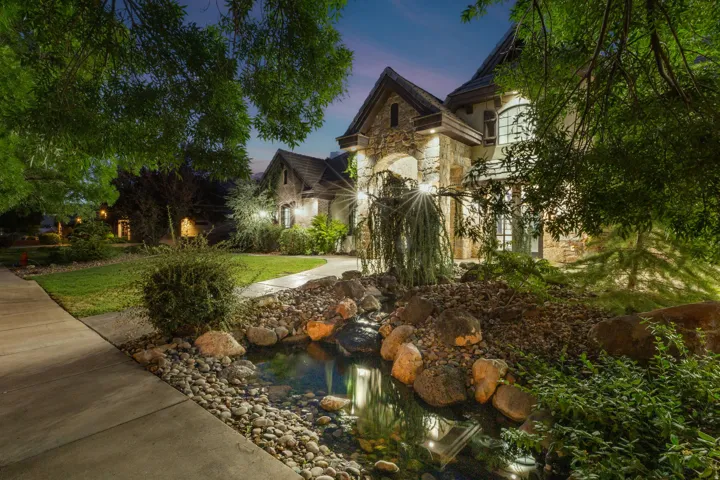Stone façade residence featuring arched entryways, a turret-style architectural element, and multiple dormer windows