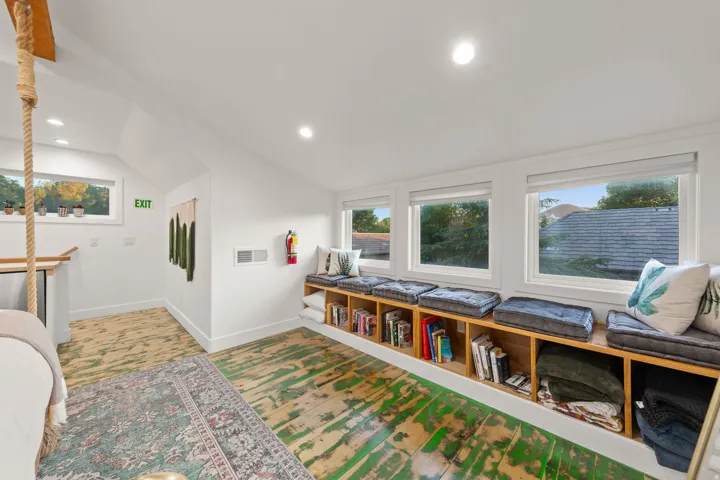 Upper-level room featuring an integrated window seat with storage, multiple windows, recessed lighting, and distressed wood-finish flooring